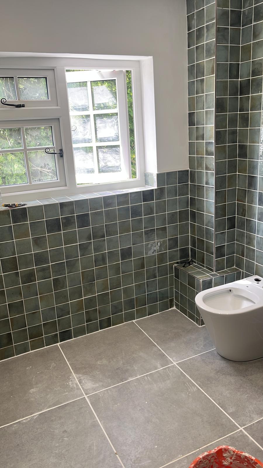 Finished bathroom with green wall tiles and large grey floor tiles