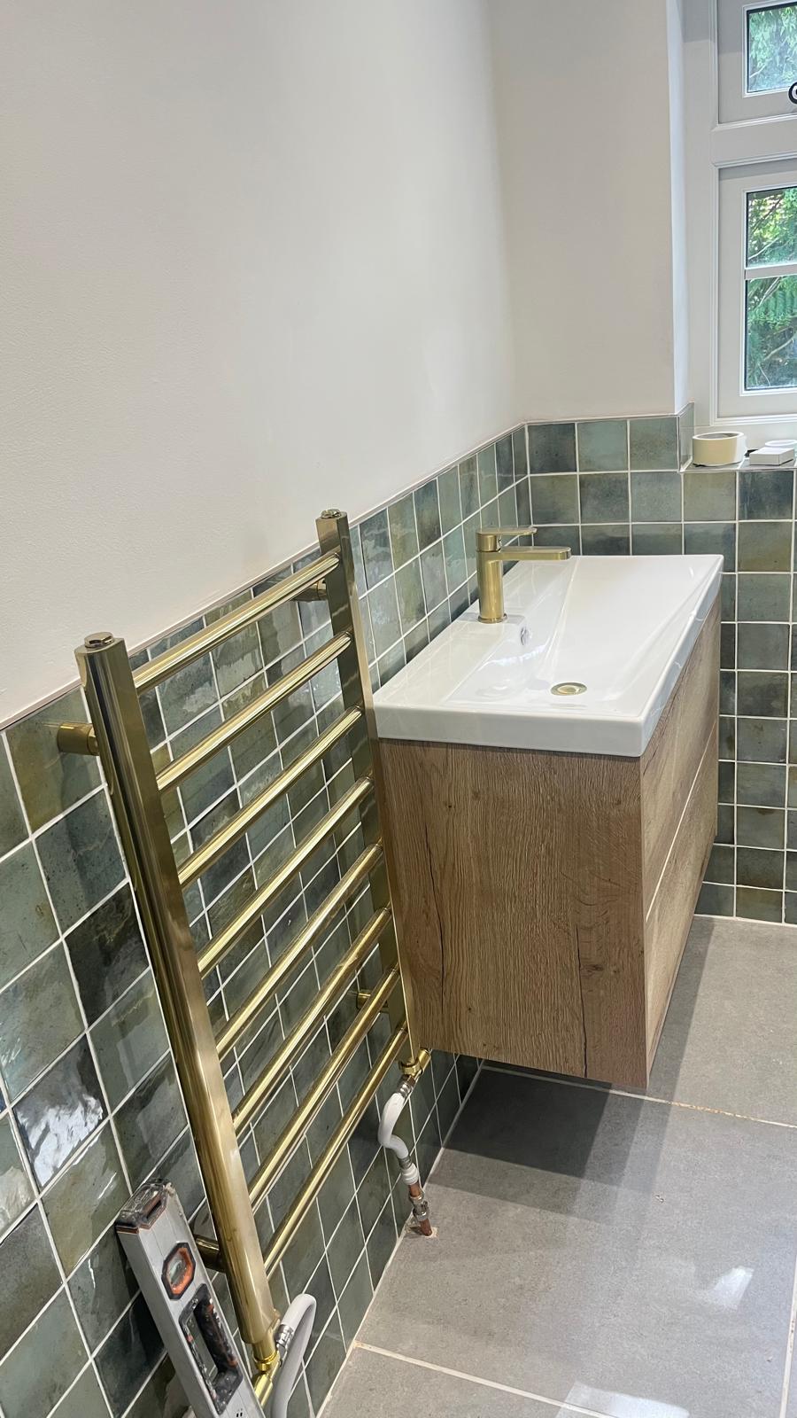 Brass towel radiator next to an oak vanity unit