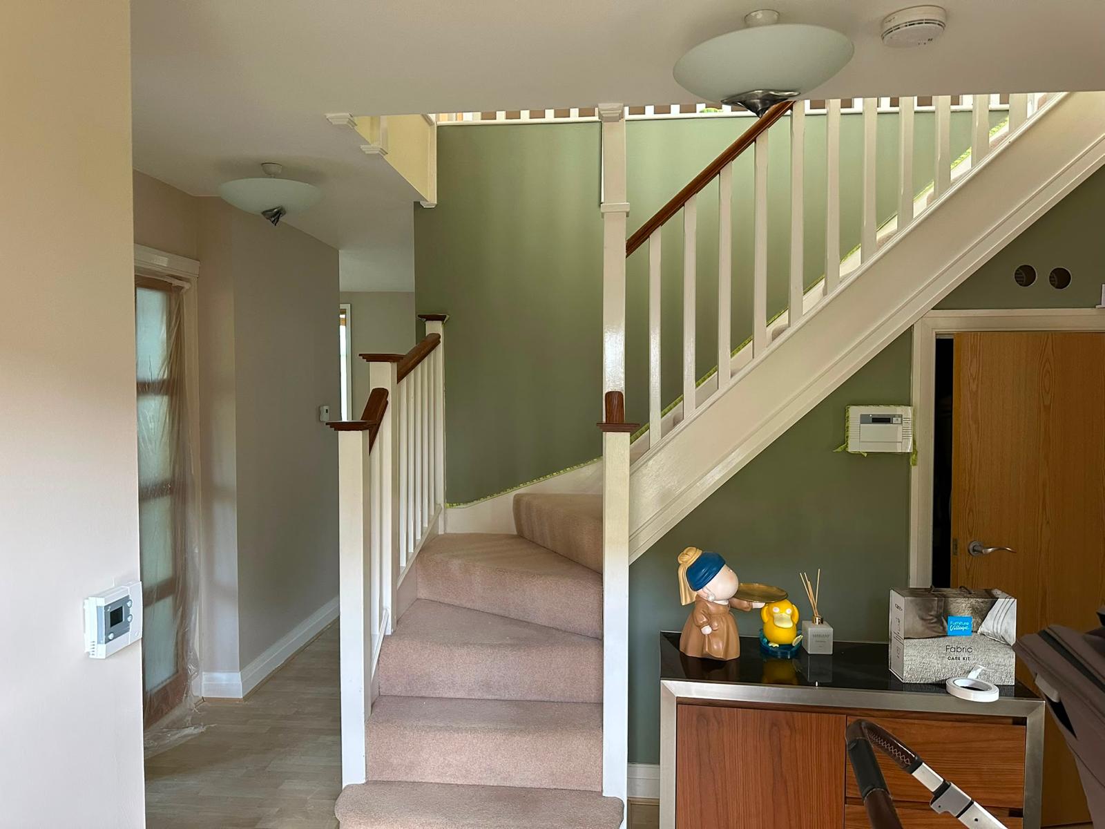 Hallway staircase after repainting in sage green with white banisters