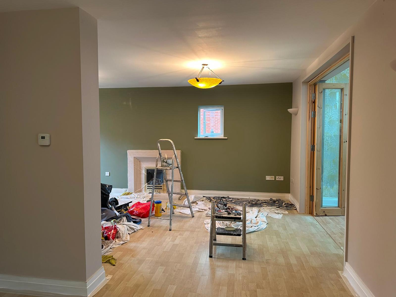Living room with a newly painted olive feature wall, work in progress