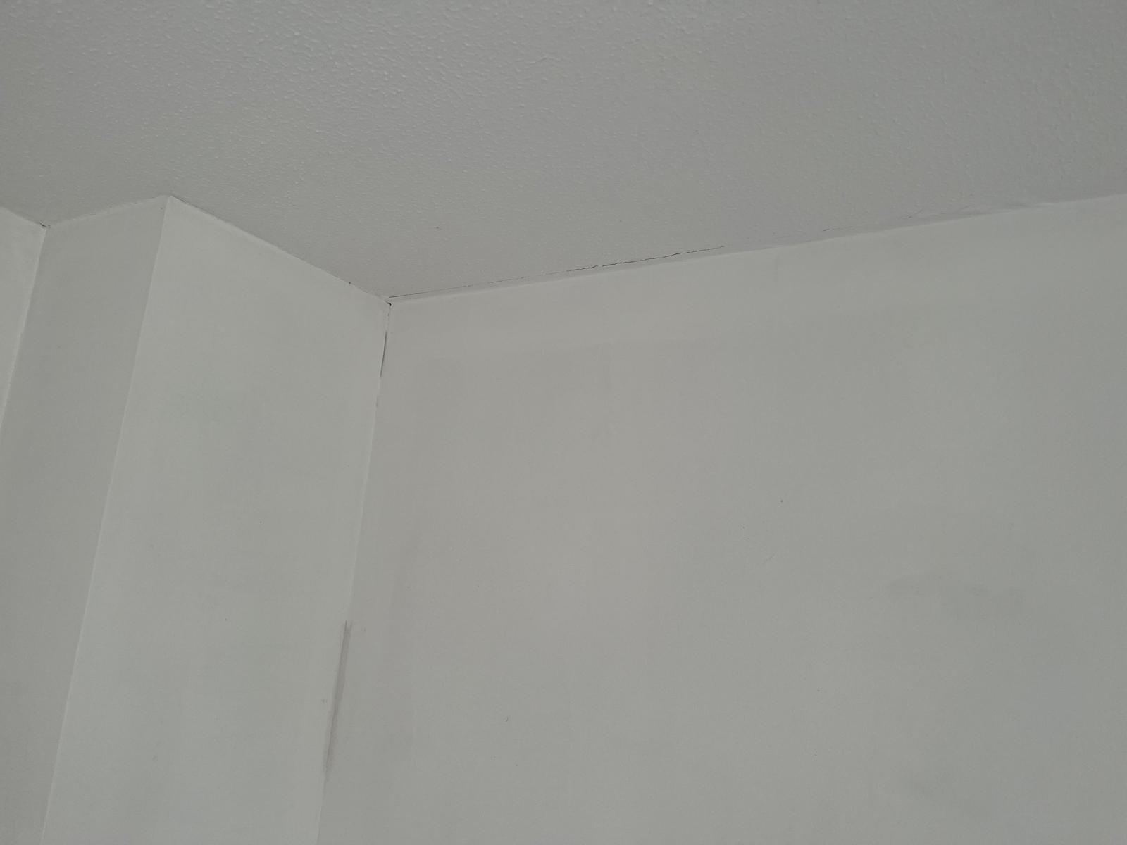 Before photo showing cracks where the wall meets the ceiling