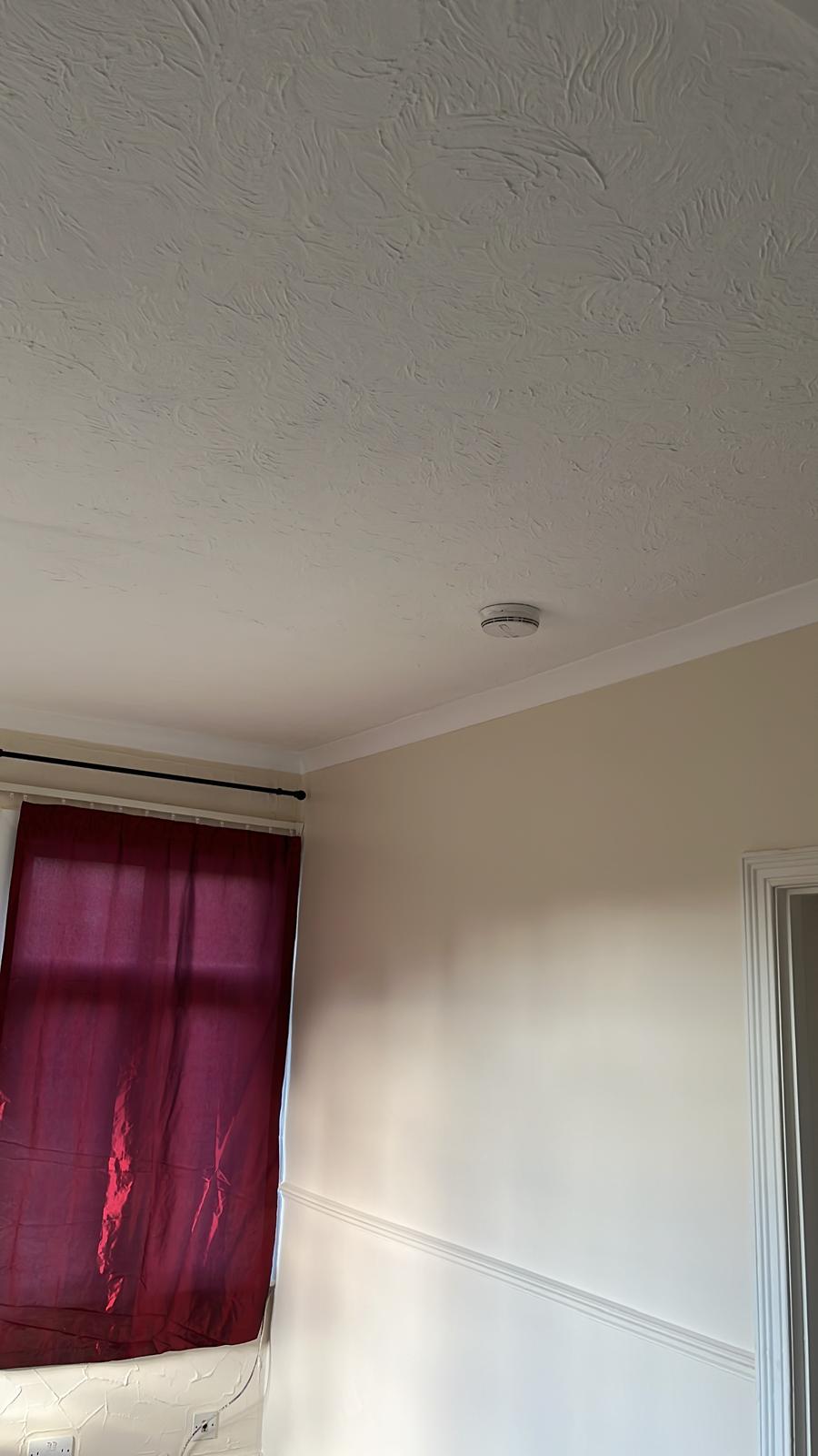 Textured ceiling, coving and cream walls in a bedroom